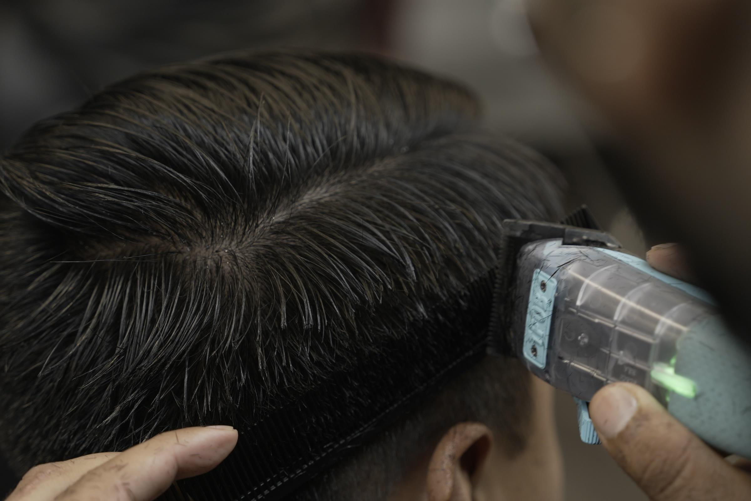 Clipper-over-comb on a fade, the comb held against the side of the head as a guide and the clippers riding along its edge.